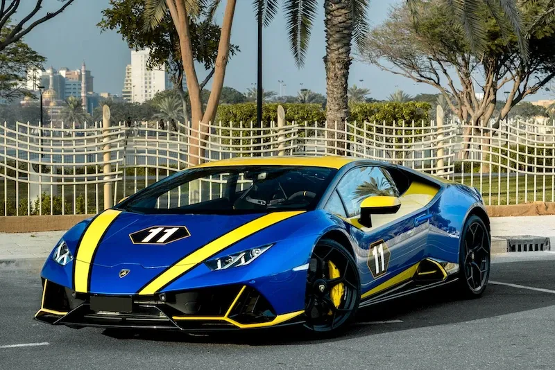 Front view of Lamborghini Huracan Evo Daytona 24h Winner 2019 in blue and yellow livery parked near palm trees.