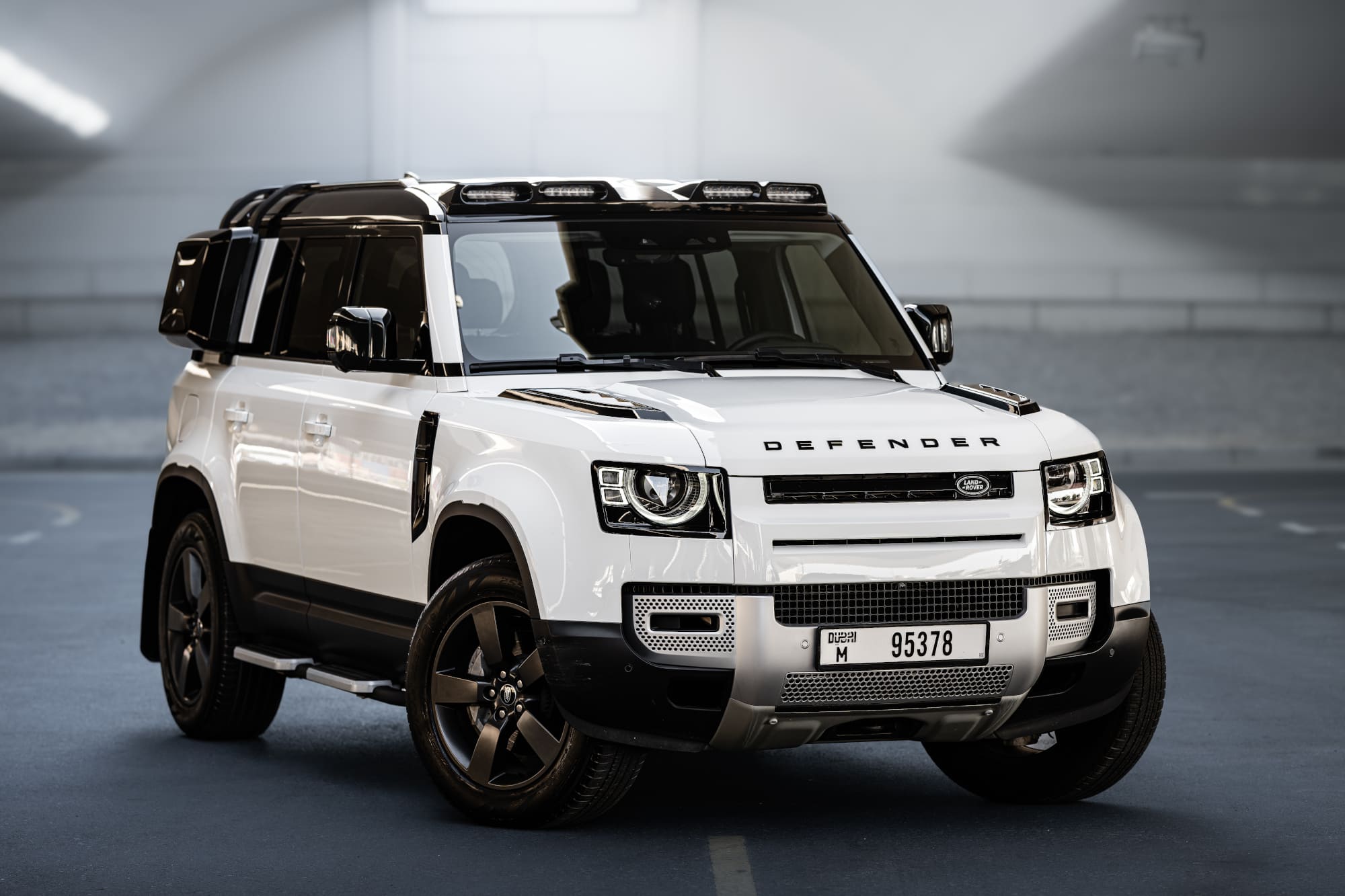White Land Rover Defender luxury SUV rental in Dubai parked in modern tunnel setting