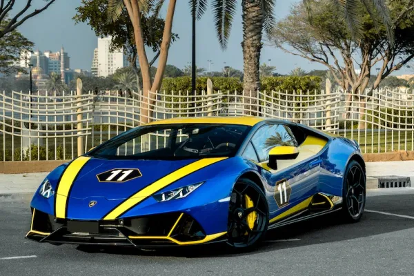 Front view of Lamborghini Huracan Evo Daytona 24h Winner 2019 in blue and yellow livery parked near palm trees.